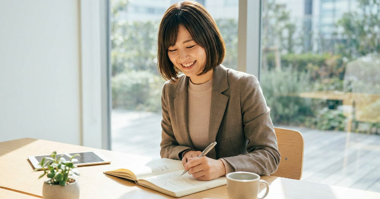 左手でペンを持ち、快適な書き心地に笑顔を見せるビジネスウーマン